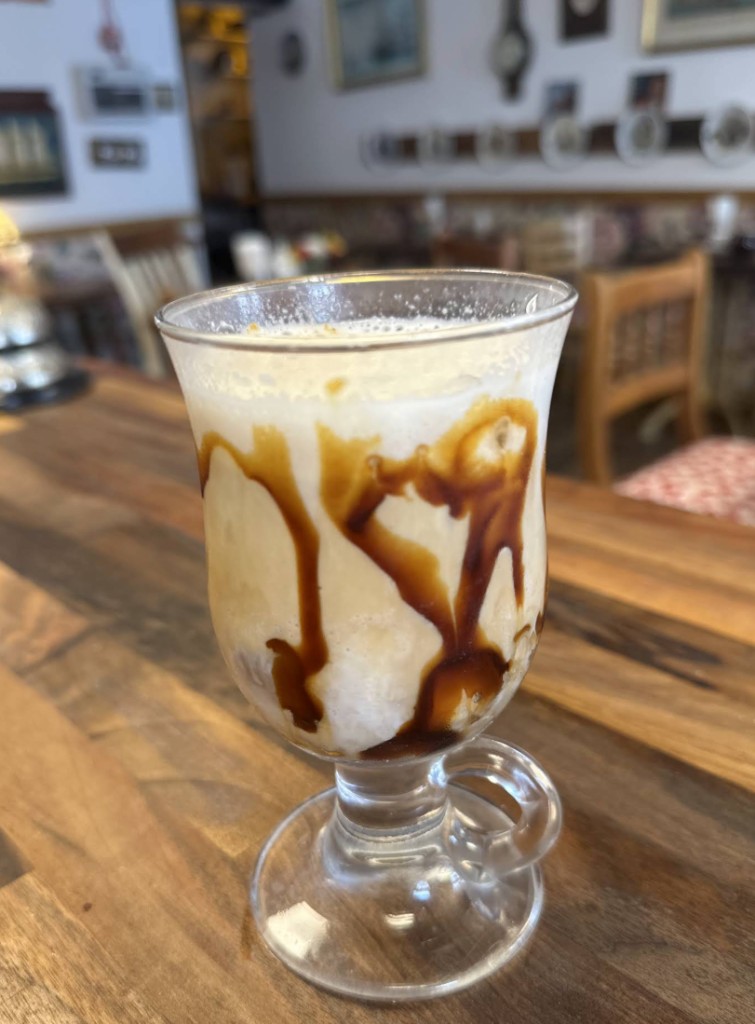 Specialty coffee drink at The Vintage Vault in Sheerness: frothy drink with chocolate drizzle in a glass mug