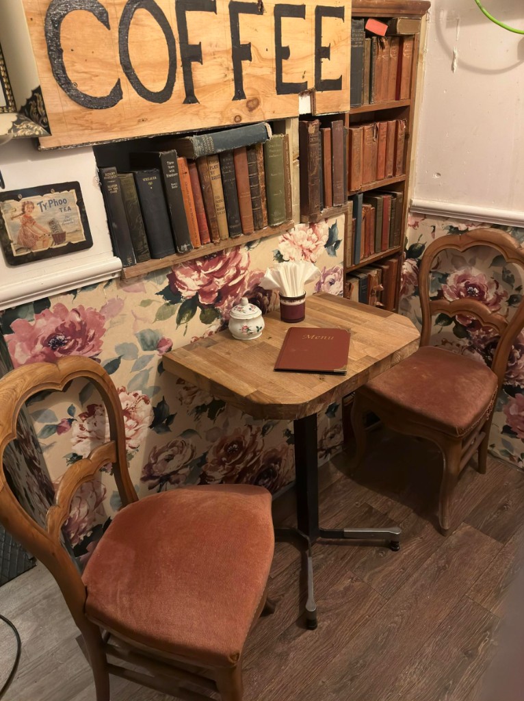 Vintage corner at The Vintage Vault coffee shop in Sheerness: table, chairs, bookshelves and COFFEE sign