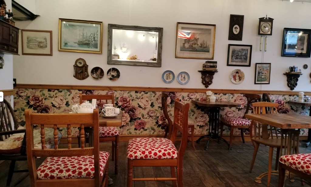 Vintage tea room at The Vintage Vault coffee shop in Sheerness: floral wallpaper, wooden tables and chairs, mirrors and wall decor