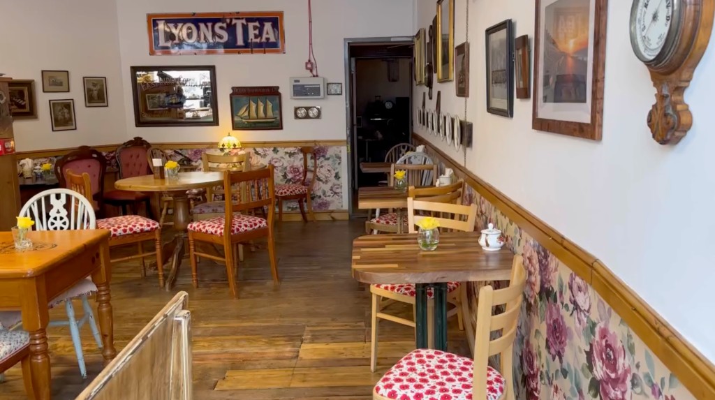Cosy seating at The Vintage Vault: wooden tables and chairs, floral wallpaper, vintage signs
